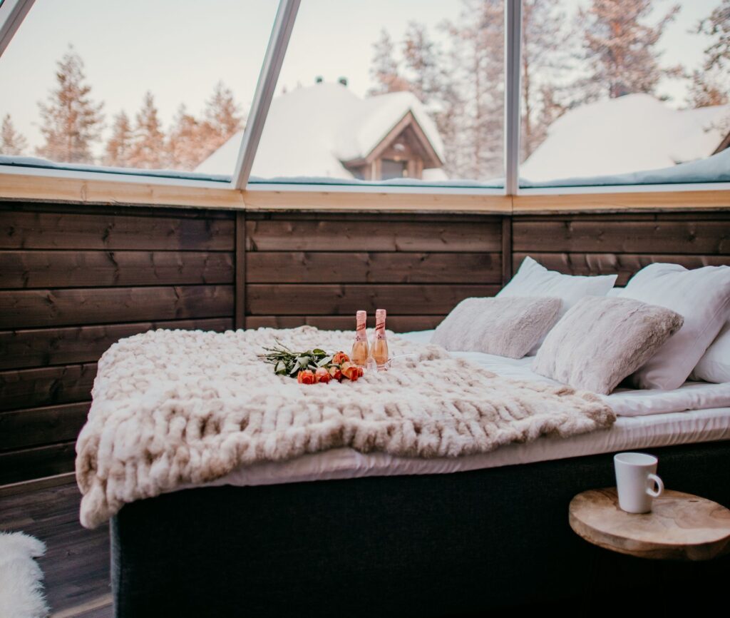 Bed onder het glazen dak van een Aurora Cabin in Muotka